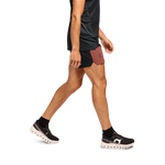 Man running in black On 5-inch lightweight shorts with rust accent panel