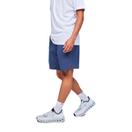 Man wearing navy blue On Focus shorts with white shirt and light blue sneakers