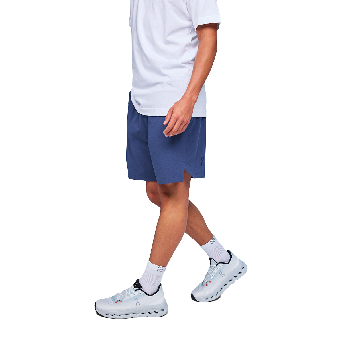Man wearing navy blue On Focus shorts with white shirt and light blue sneakers