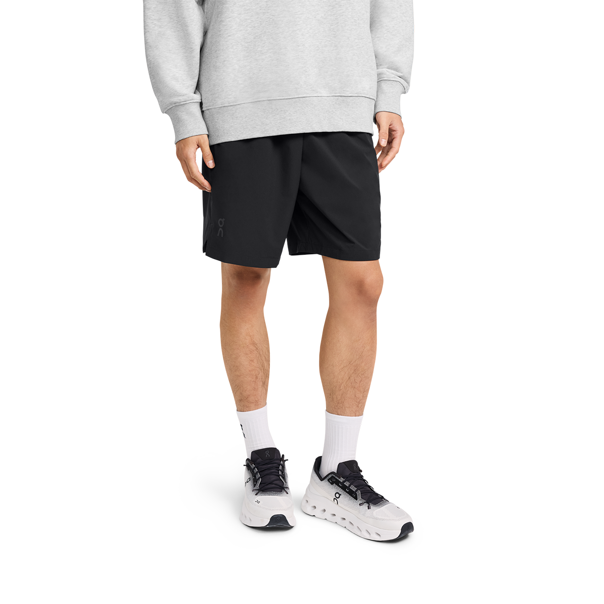 Man wearing black On Focus Shorts with gray sweatshirt and white running shoes