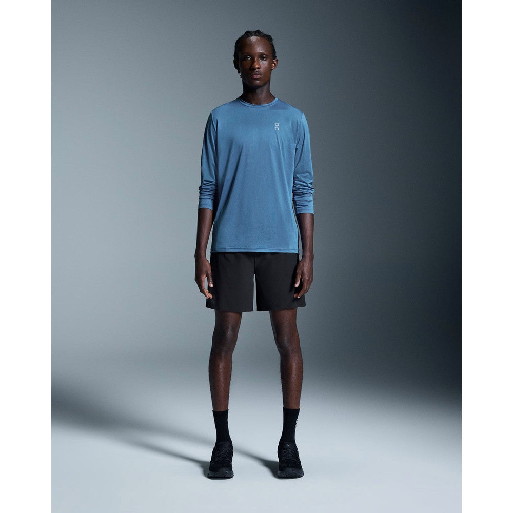 Male model wearing black On Running performance shorts with blue long-sleeve shirt