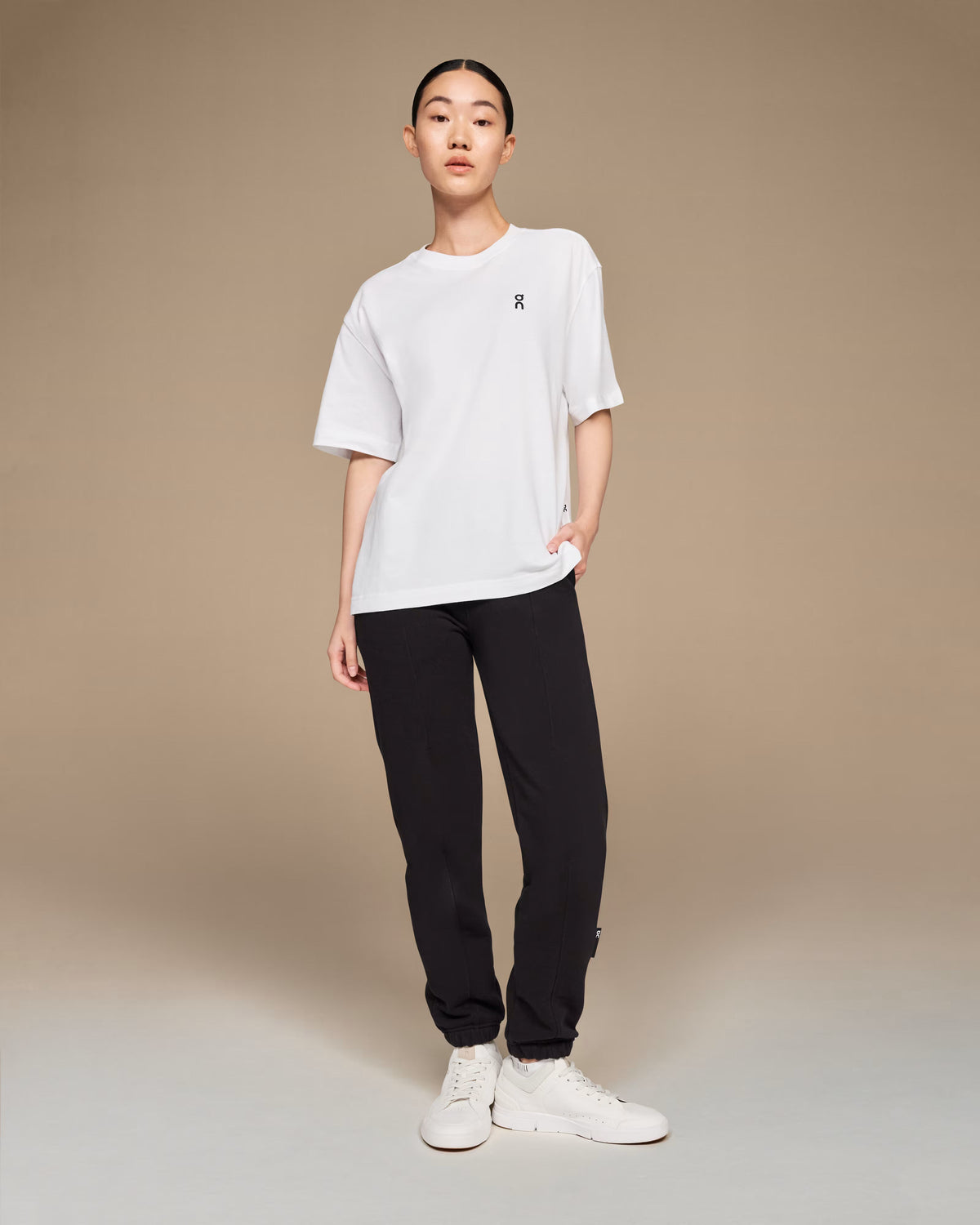 On Running Club-T white t-shirt full body view styled with black joggers and white sneakers