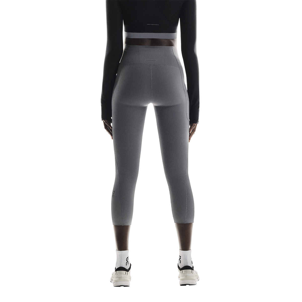 Woman wearing gray On Studio Tights 7/8 leggings from behind on white background