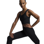 Woman wearing black On Studio Tights and sports bra in athletic pose