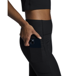 Woman wearing black On Studio Tights with side pocket holding smartphone