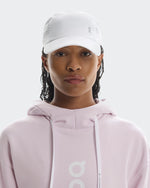 Model wearing white On Lightweight Unisex Cap with ventilation holes and pink hoodie