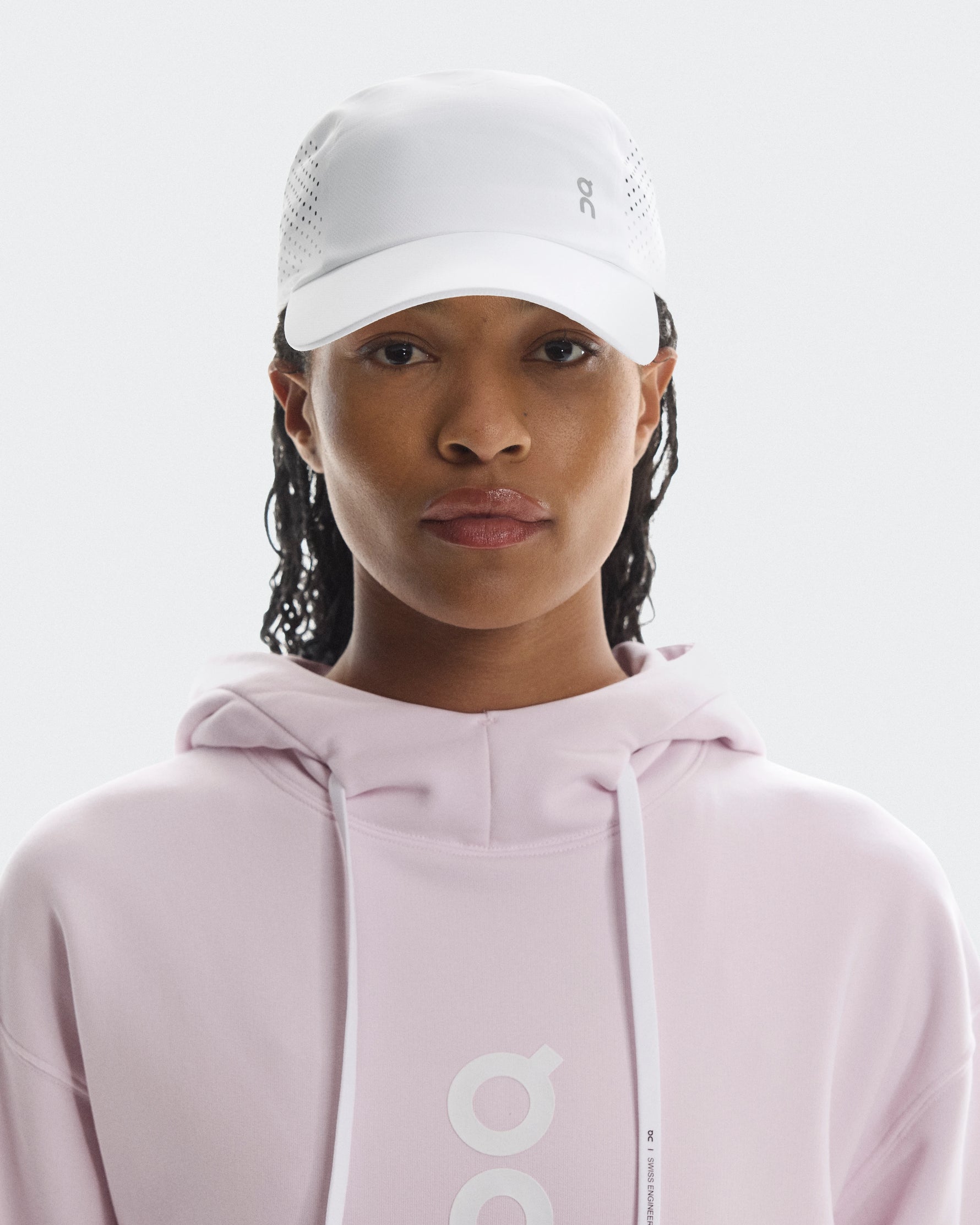 Model wearing white On Lightweight Unisex Cap with ventilation holes and pink hoodie