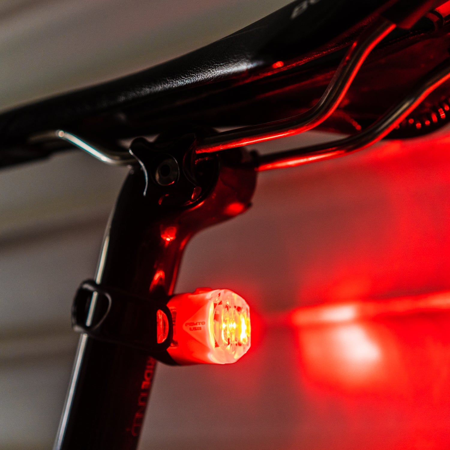 Lezyne FEMTO USB rear bike light in black mounted on bicycle seatpost, glowing red