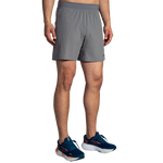 Man wearing gray Brooks Sherpa 7-inch running shorts with navy athletic shoes