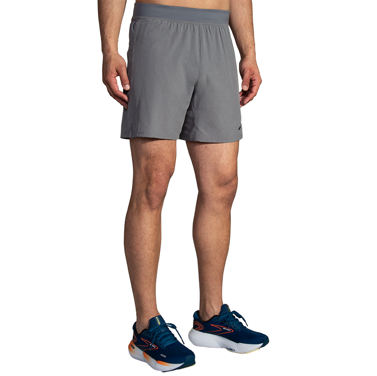 Man wearing gray Brooks Sherpa 7-inch running shorts with navy athletic shoes