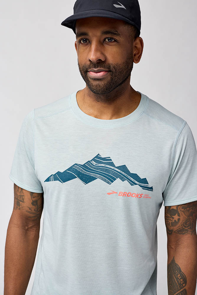 Man wearing Brooks Distance Short Sleeve 3.0 in light ash blue with mountain graphic