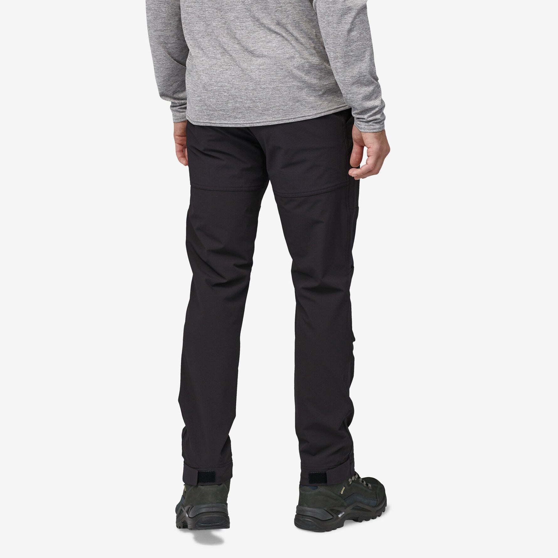 Man wearing black Patagonia Point Peak Trail Pants with gray top and hiking shoes