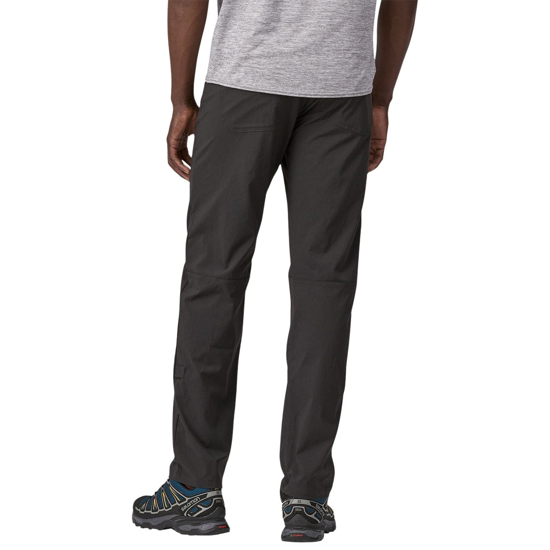 Man wearing dark green Patagonia Quandary pants with hiking shoes on white background