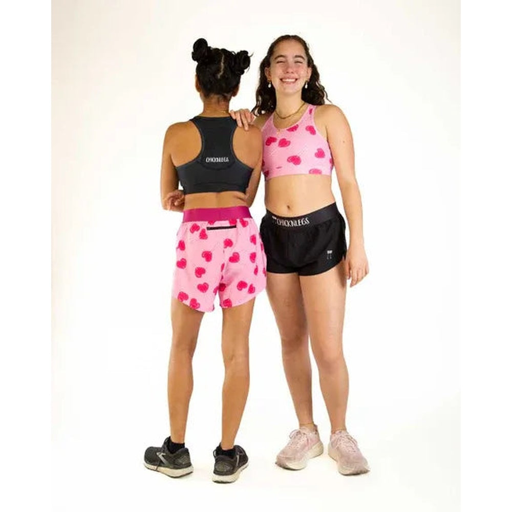Two models wearing ChicknLegs Luv Pops sports bras and shorts in pink heart pattern