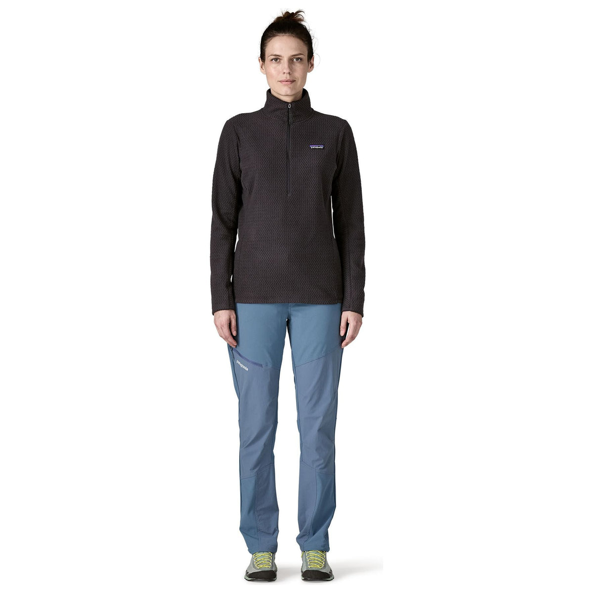 Woman wearing black Patagonia R1 Air Fleece Zip-Neck with blue pants, full body front view