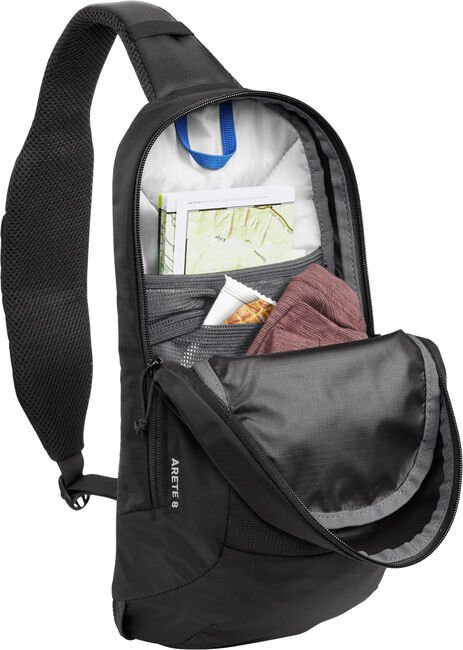 Black CamelBak Arete sling bag opened showing interior compartments and organization pockets