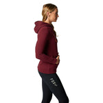 Woman wearing Fox Racing burgundy pullover hoodie with black leggings, side profile view