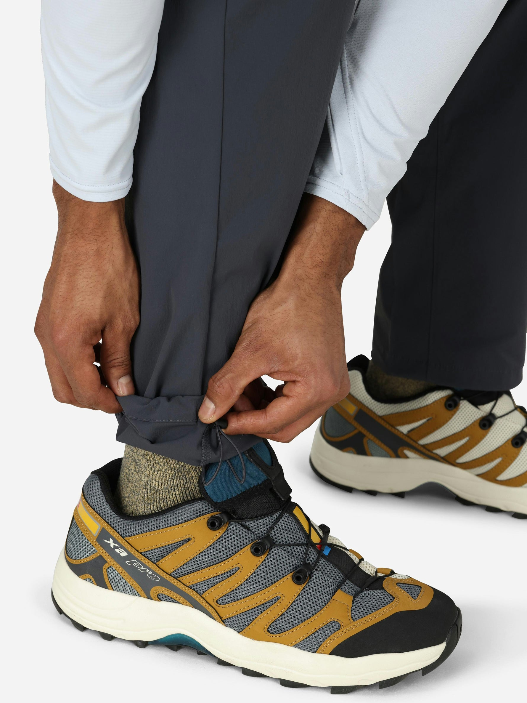 Person adjusting gray convertible pants leg while wearing outdoor hiking shoes
