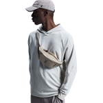 Model wearing beige On waist pack across chest with gray hoodie and cap