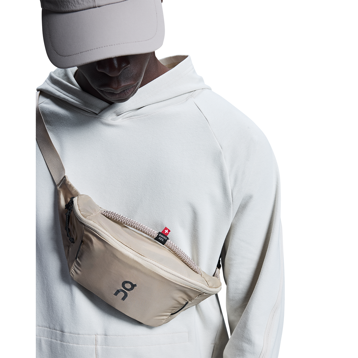 On Waist Pack 2L Lite in sand color worn across chest by model
