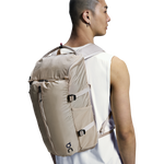 Man wearing On Speed Pack 18L Lite backpack in cream sand colorway, rear view