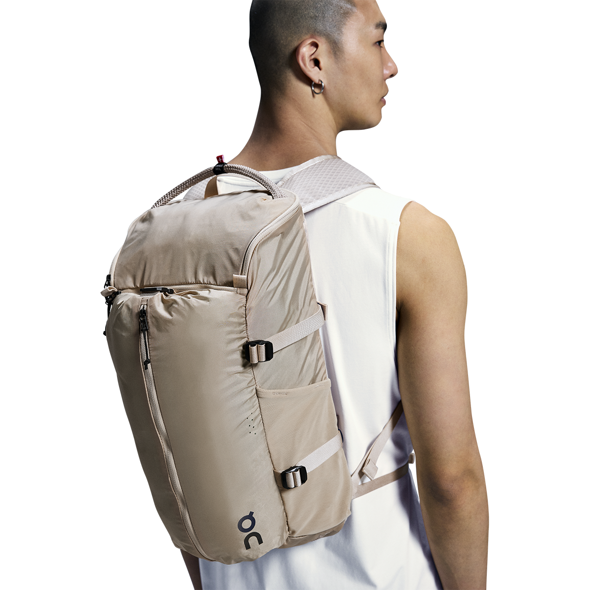Man wearing On Speed Pack 18L Lite backpack in cream sand colorway, rear view