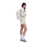 Model wearing On Speed Pack 18L Lite backpack in cream with matching On athletic outfit