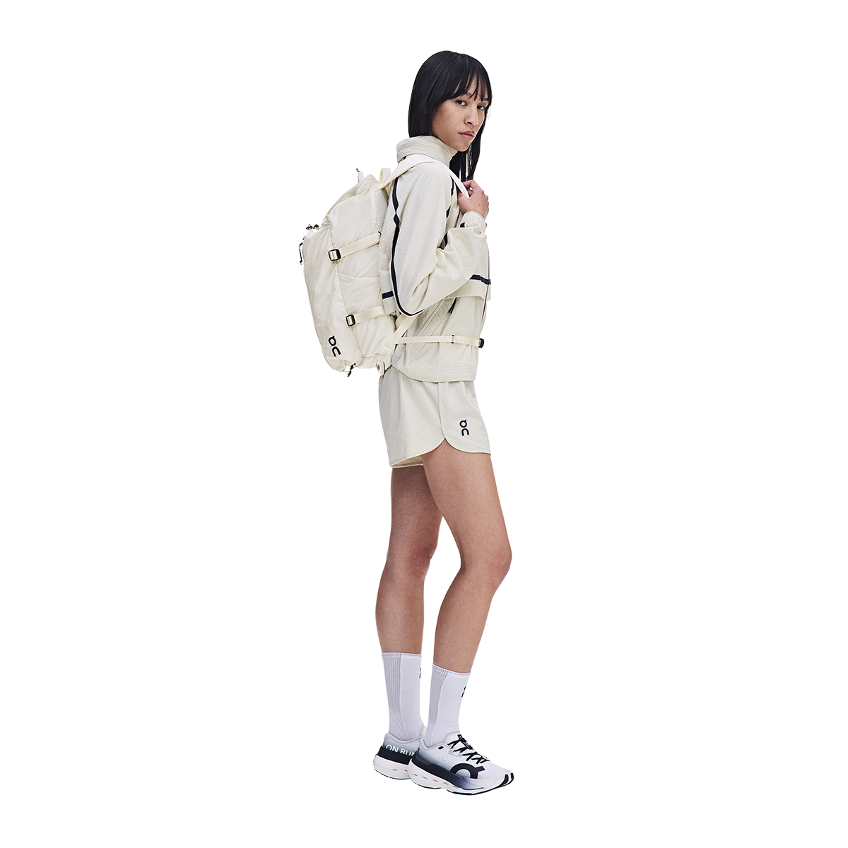 Model wearing On Speed Pack 18L Lite backpack in cream with matching On athletic outfit