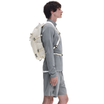 Male model wearing On Speed Pack 18L Lite backpack in cream with gray athletic outfit