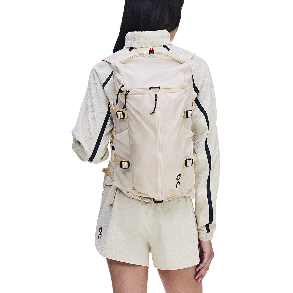 Woman wearing On Speed Pack 18L Lite backpack in cream color, rear view