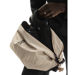 On Sling Pack 9L in Biscuit being loaded with black On running shoes