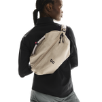 On Sling Pack 9L in Biscuit worn as crossbody bag on model in black jacket