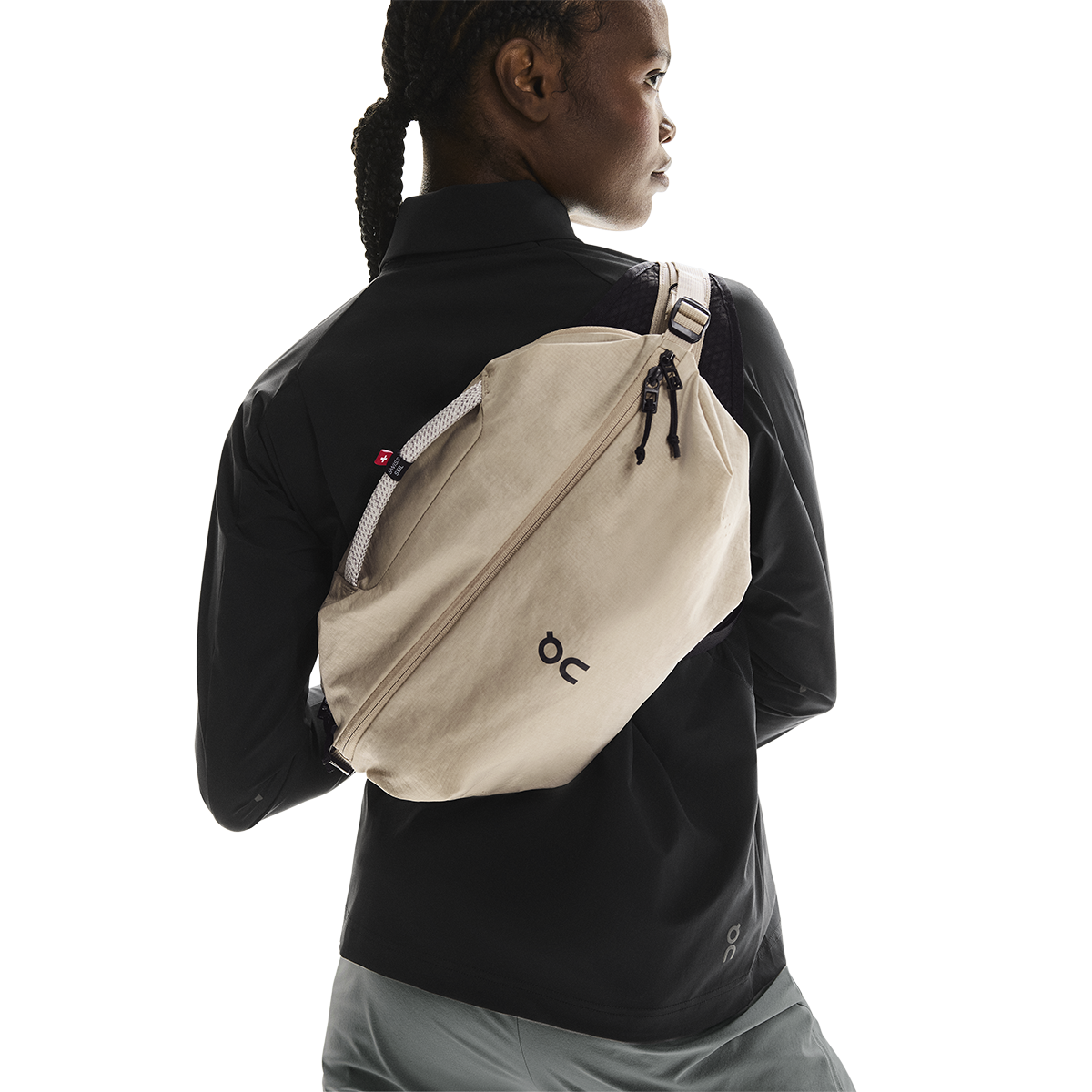 On Sling Pack 9L in Biscuit worn as crossbody bag on model in black jacket