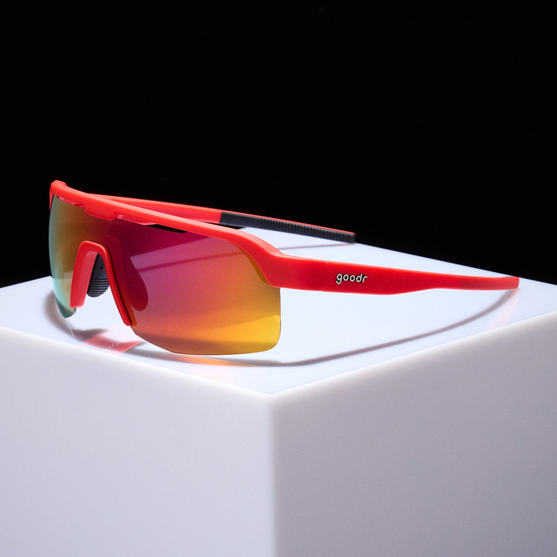 Goodr red sports sunglasses with orange gradient mirrored lenses on white surface
