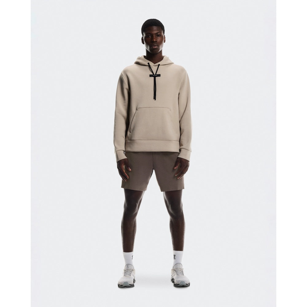 Man wearing beige On Focus Tech Hoodie with matching shorts and white sneakers