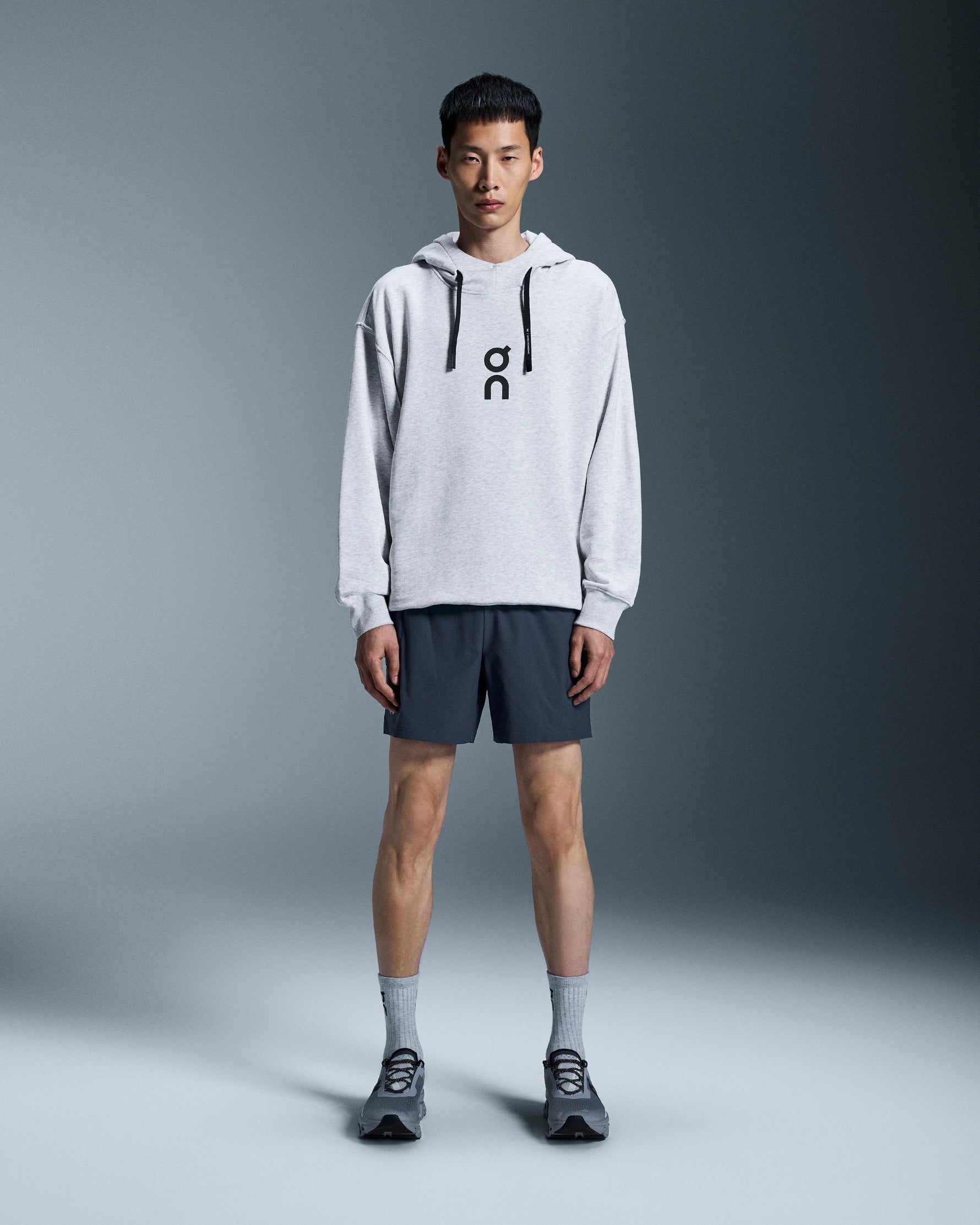 Man wearing On 5 inch Core Shorts in navy blue with grey hoodie