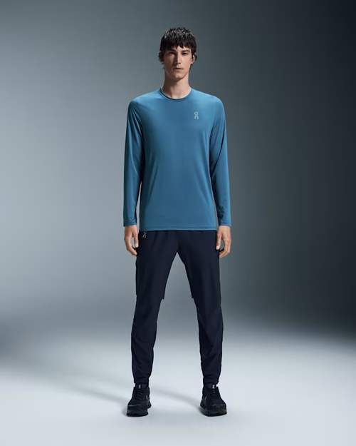 Man wearing blue On Core Long-T shirt with navy pants in studio