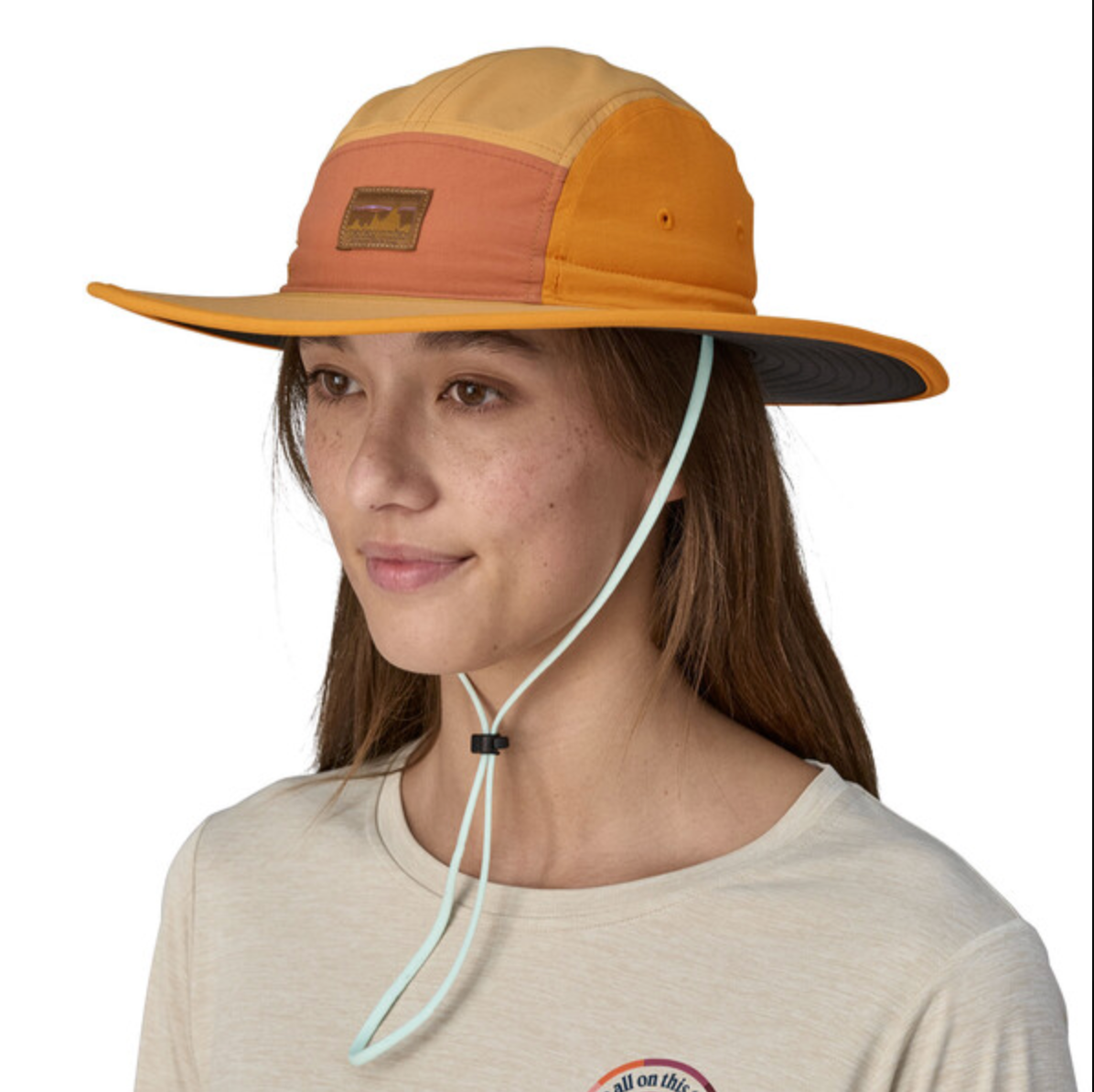 Woman wearing Patagonia Quandary Brimmer hat in orange colorblock with chin strap