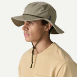 Man wearing olive green Patagonia Brimmer Hat with chin strap and wide brim