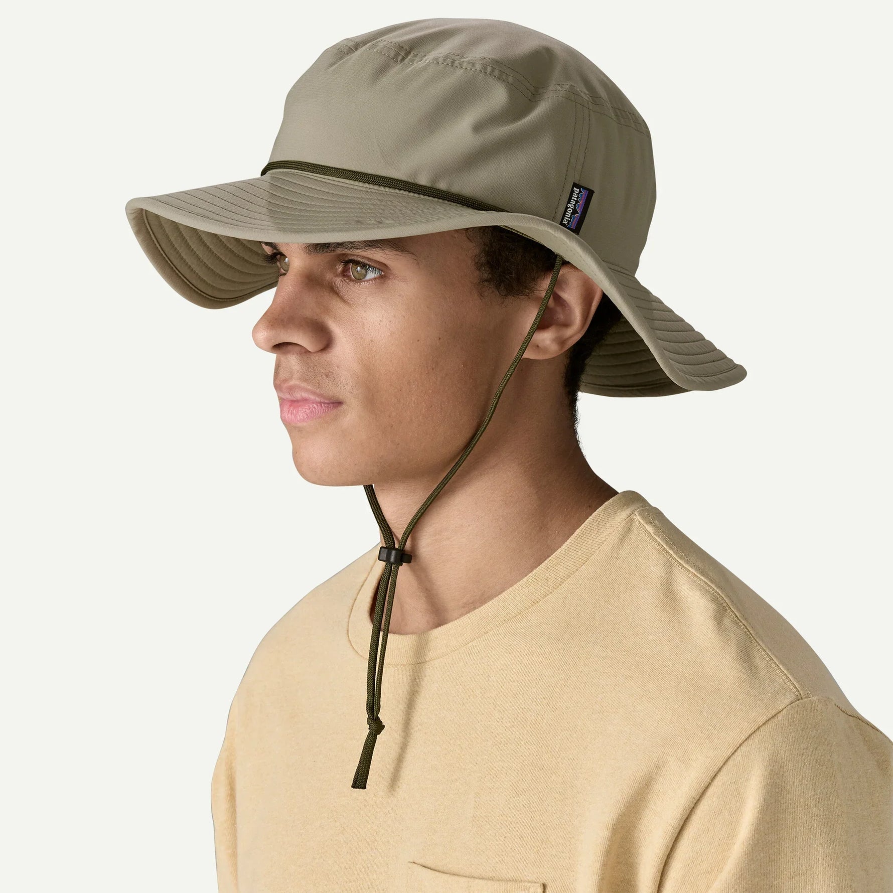 Man wearing olive green Patagonia Brimmer Hat with chin strap and wide brim