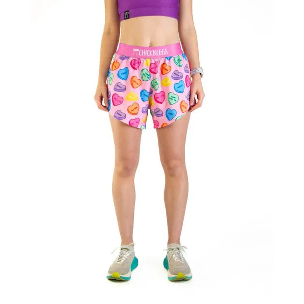 ChicknLegs women's split running shorts with colorful candy hearts pattern on pink background