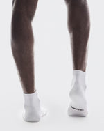 Person wearing white On running socks, showing legs in motion against clean background