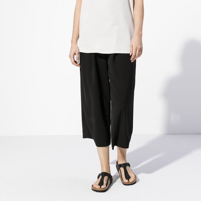 Black Birkenstock Gizeh sandals worn by model in studio setting