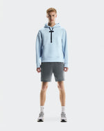 Male model wearing light blue On Focus Tech Hoodie with gray shorts and sneakers