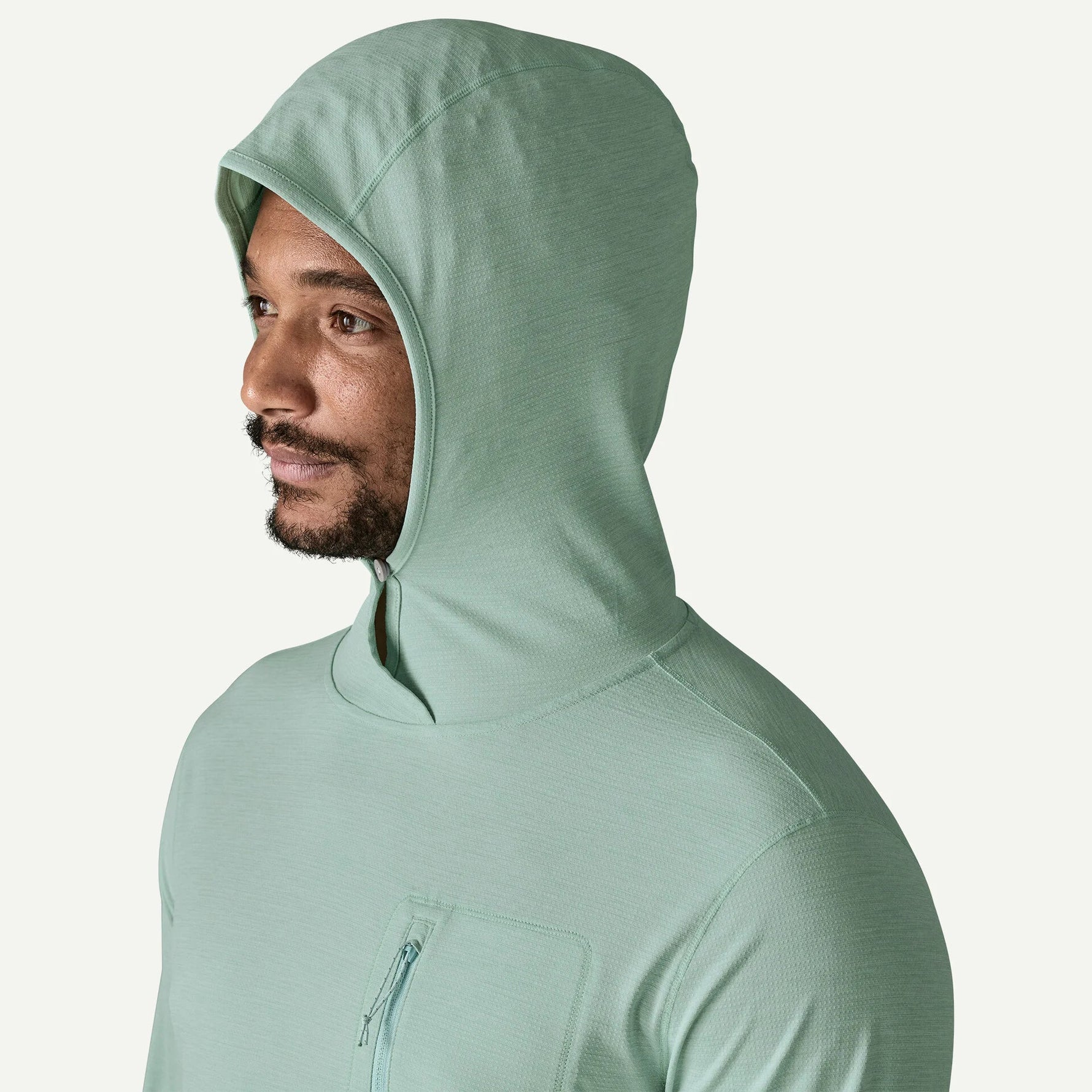 Man wearing Patagonia sage green hooded sun protection shirt with hood up