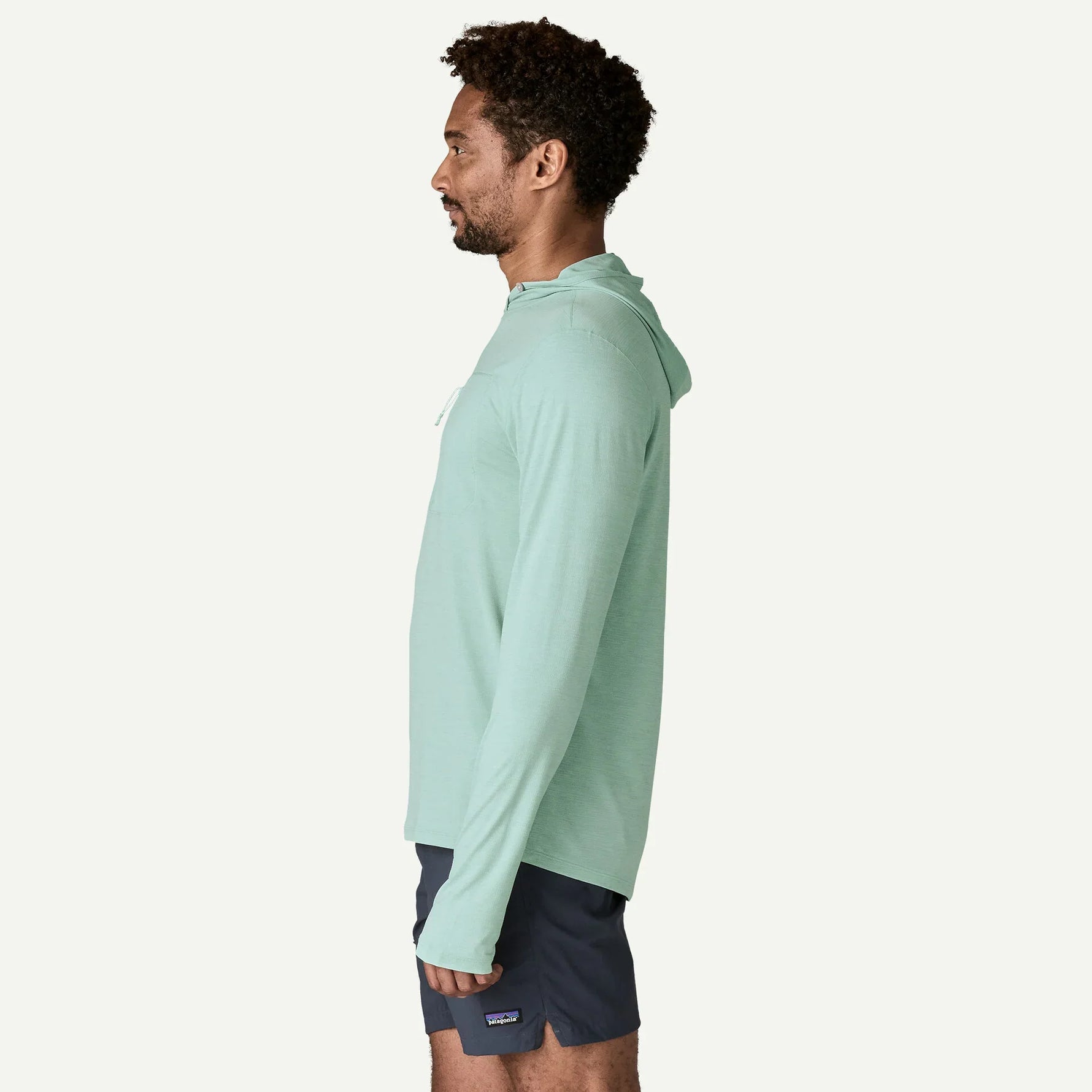 Man wearing mint green Patagonia sun hoody with hood, side profile view