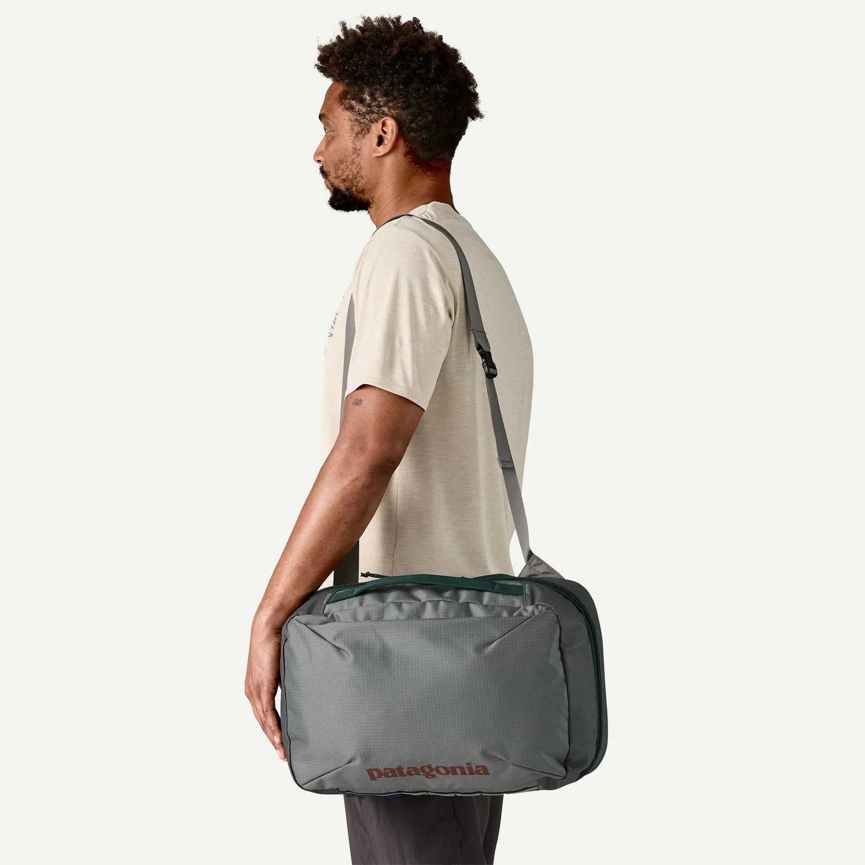 Man wearing Patagonia Black Hole MLC travel bag in sage green crossbody style