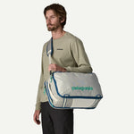 Man carrying Patagonia Black Hole Mini MLC as a duffel bag in Birch White colorway