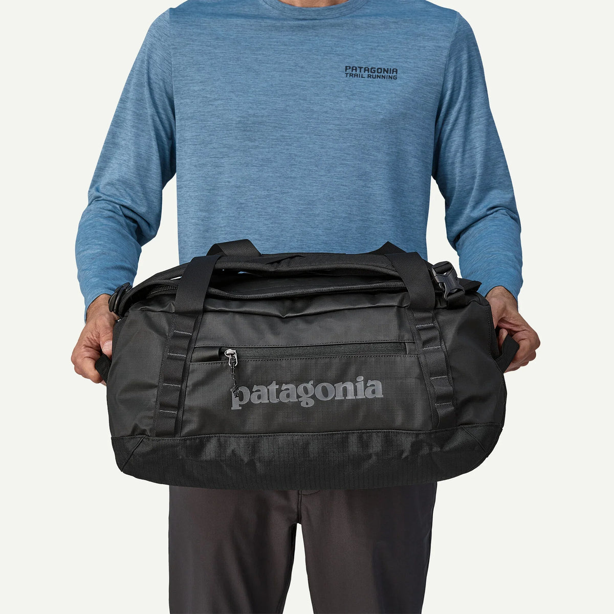 Man holding Patagonia Black Hole 40L Duffel bag in front of him, black