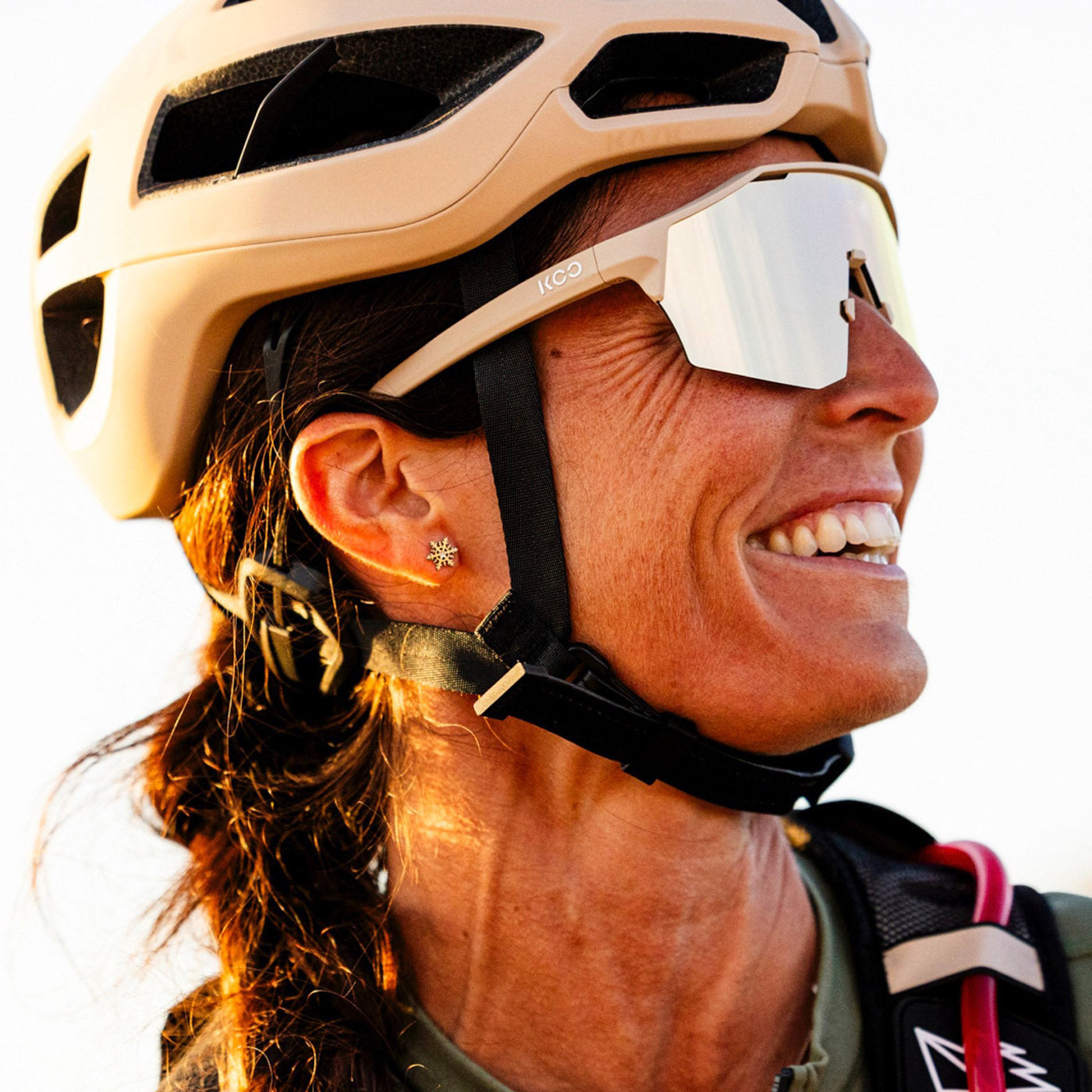 Woman wearing KOO Alibi cycling sunglasses in sand matt finish with helmet